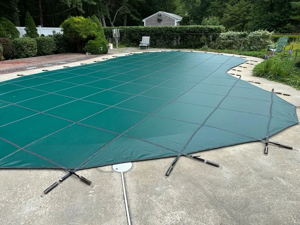 Green safety cover stretched over a residential in-ground pool